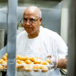 man in white crew neck t-shirt holding tray of orange fruits