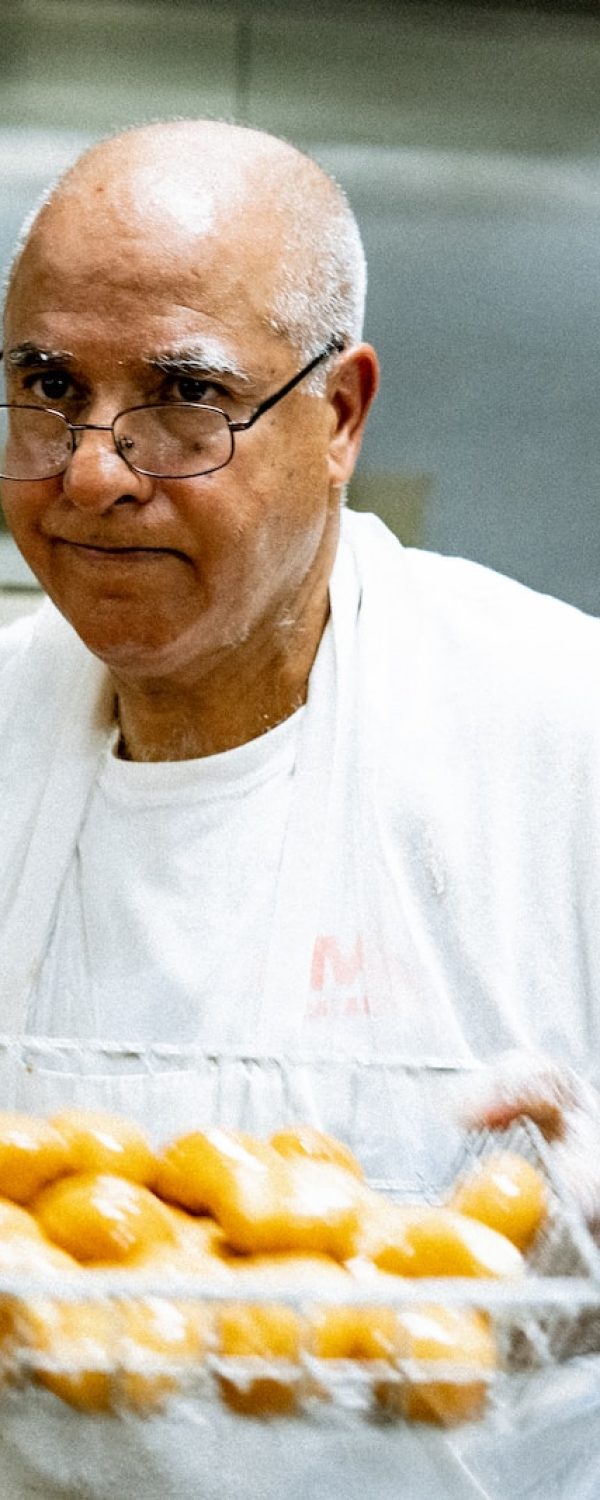 man in white crew neck t-shirt holding tray of orange fruits